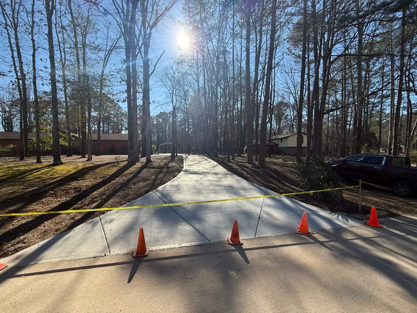 Freshly poured concrete drive taped off through the woods