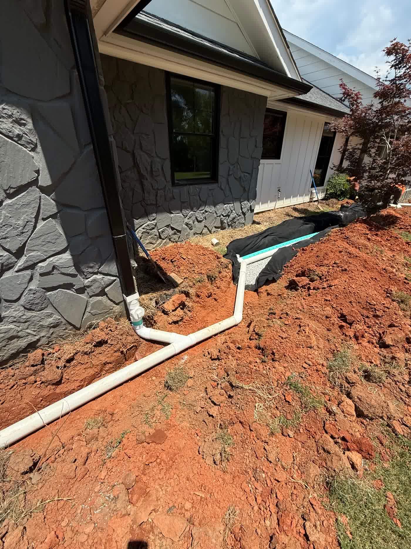 Drain pipe run along a foundation with fabric and stone