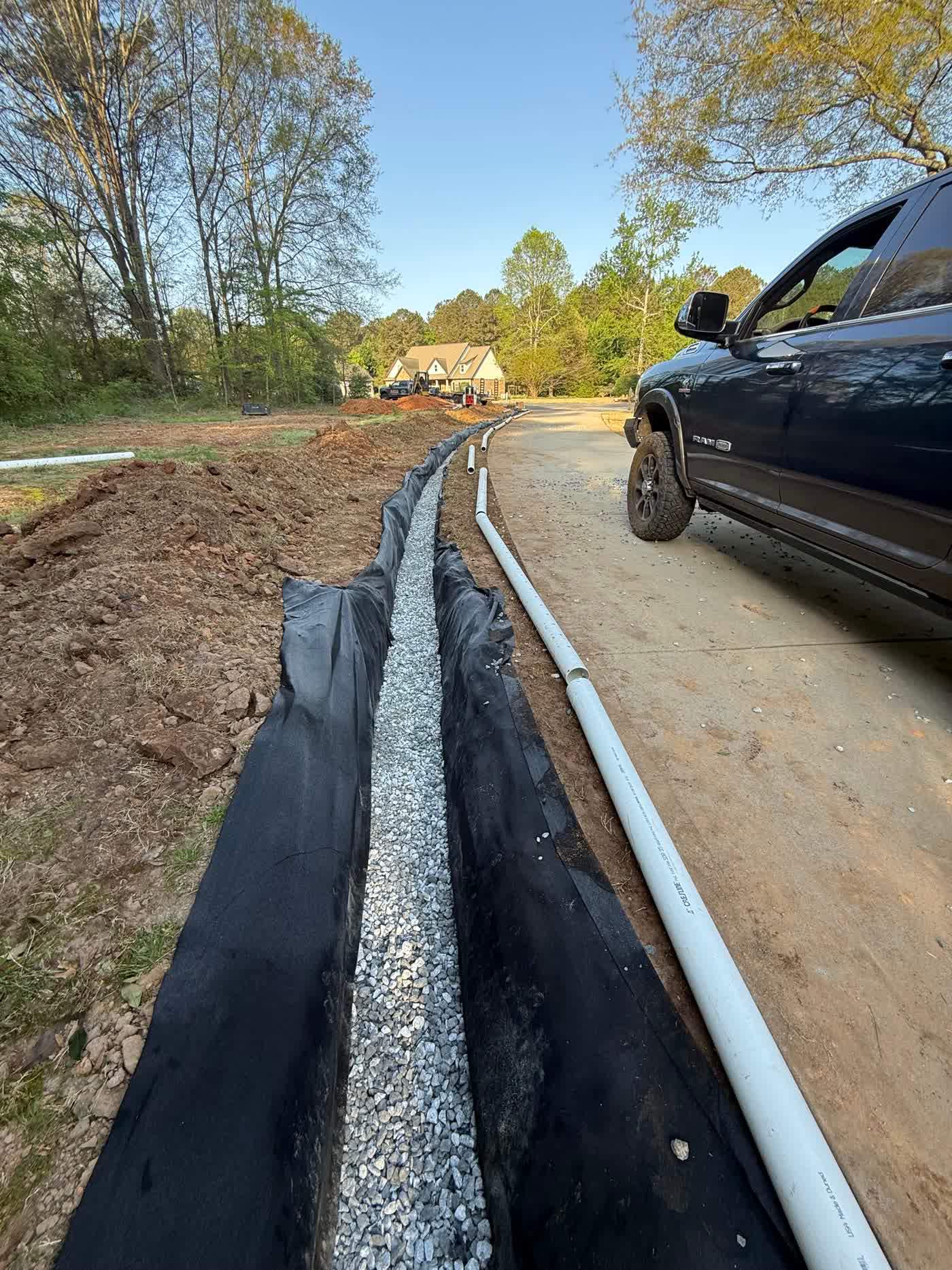 Long fabric-lined drain trench beside a driveway