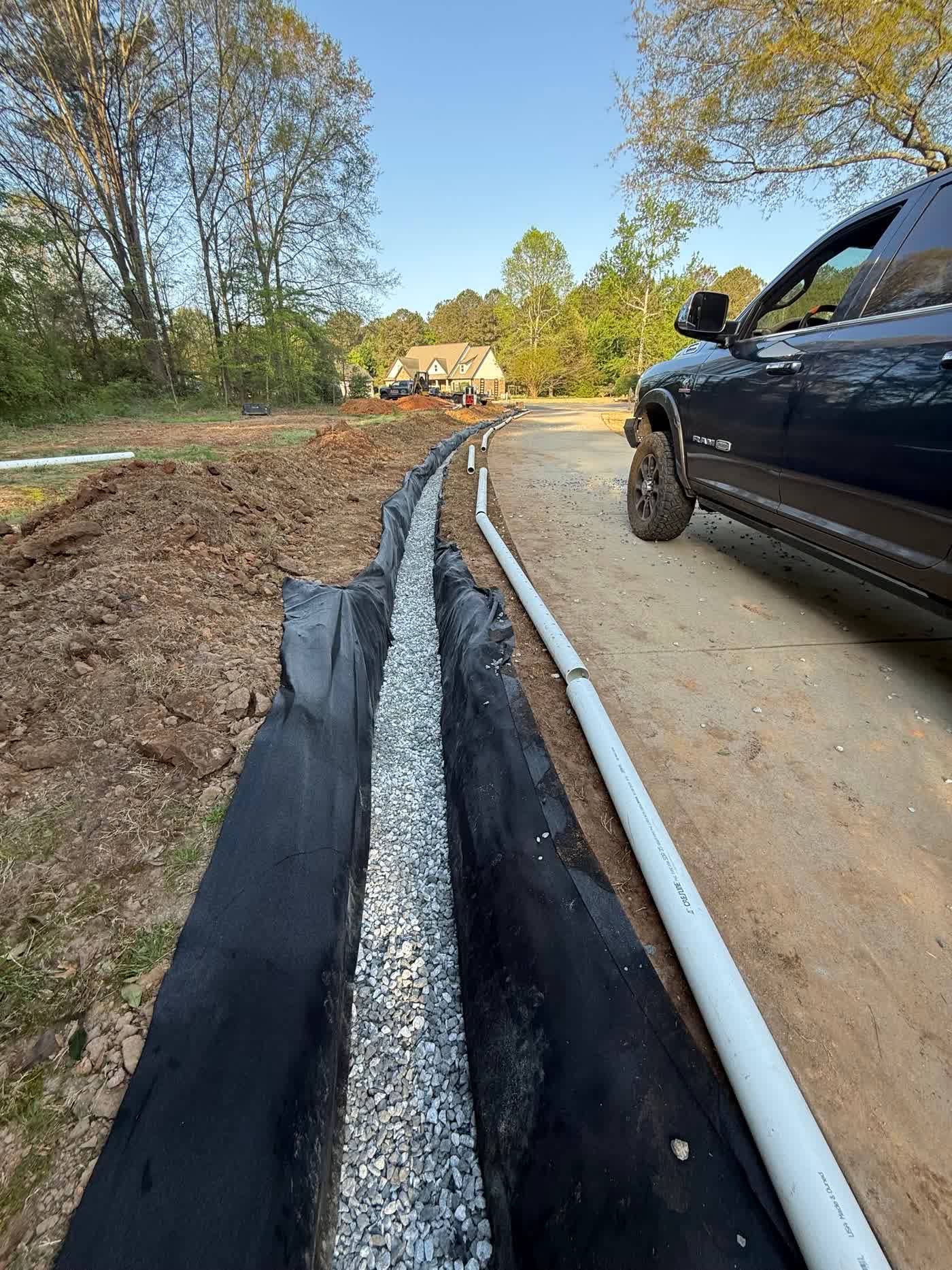 Long fabric-lined drain trench beside a driveway