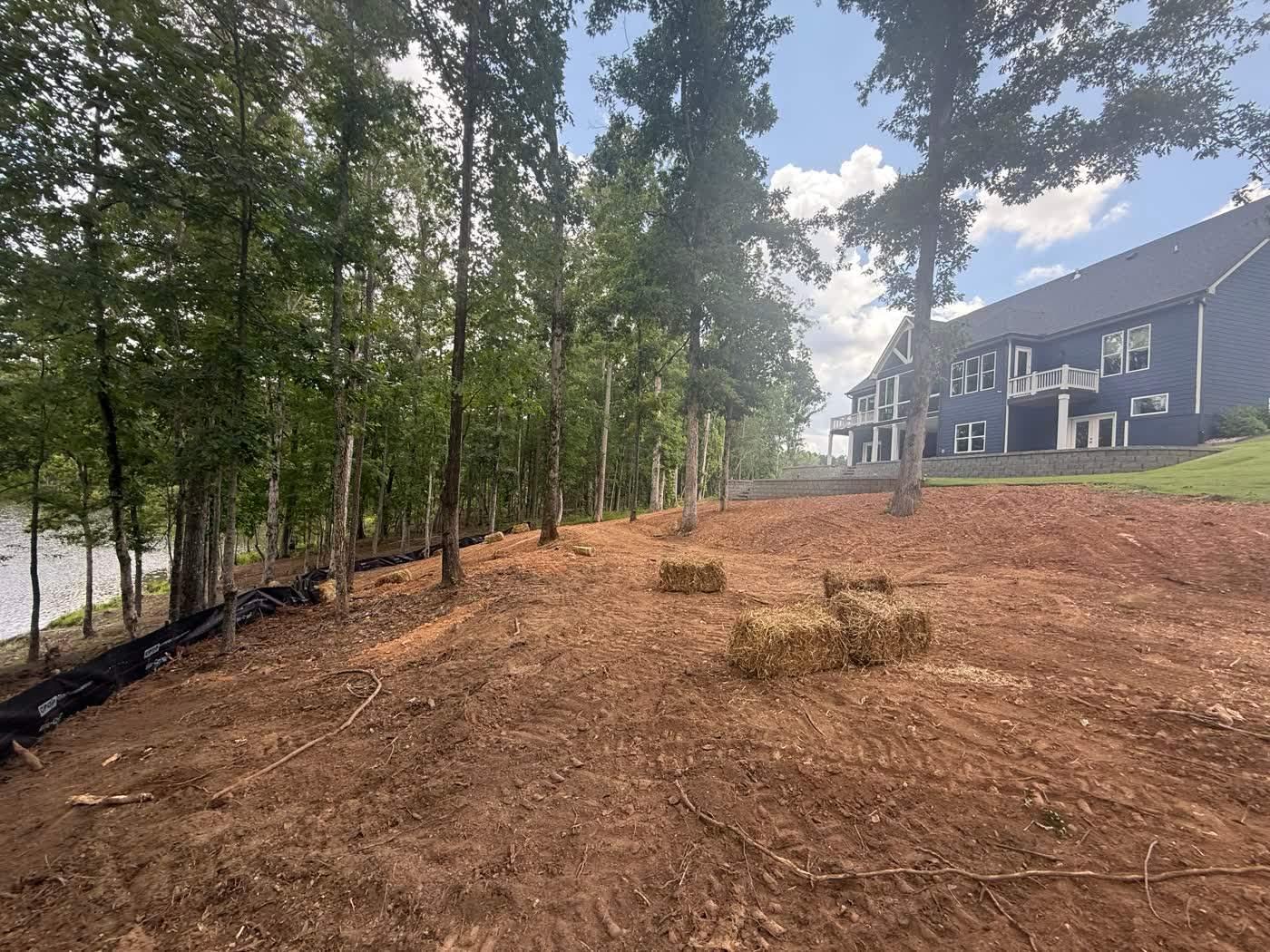 Graded lot cleared back to the treeline beside a home