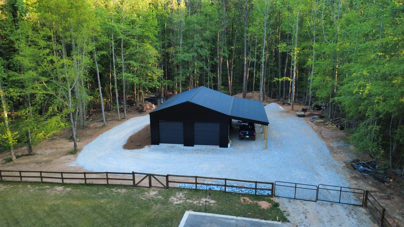 Aerial view of a gravel pad and drive around a new black barn