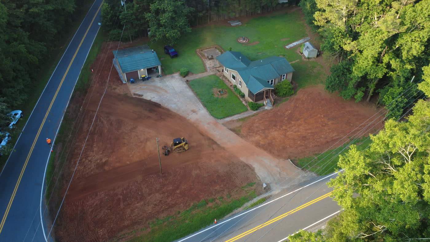 Aerial view of a graded corner lot beside a country road