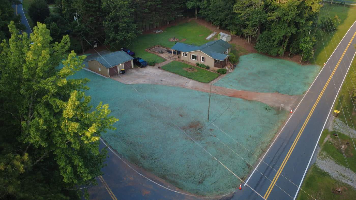 Aerial view of fresh green hydroseed covering a roadside lot