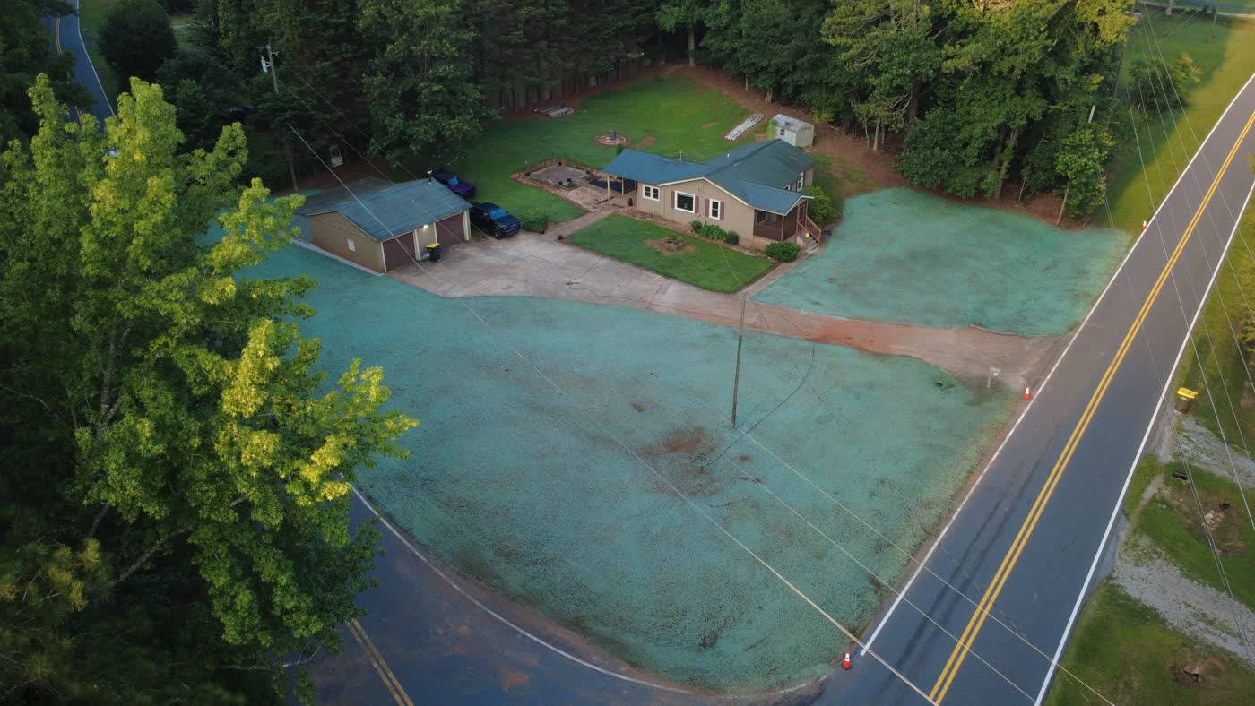 Aerial view of fresh green hydroseed covering a roadside lot