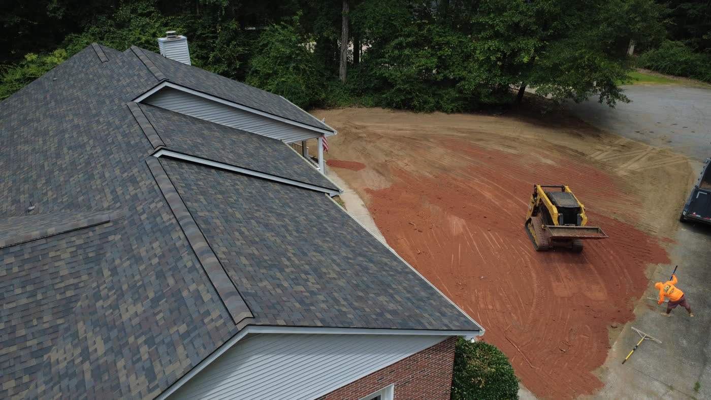 Aerial view of a graded yard beside a house roof line
