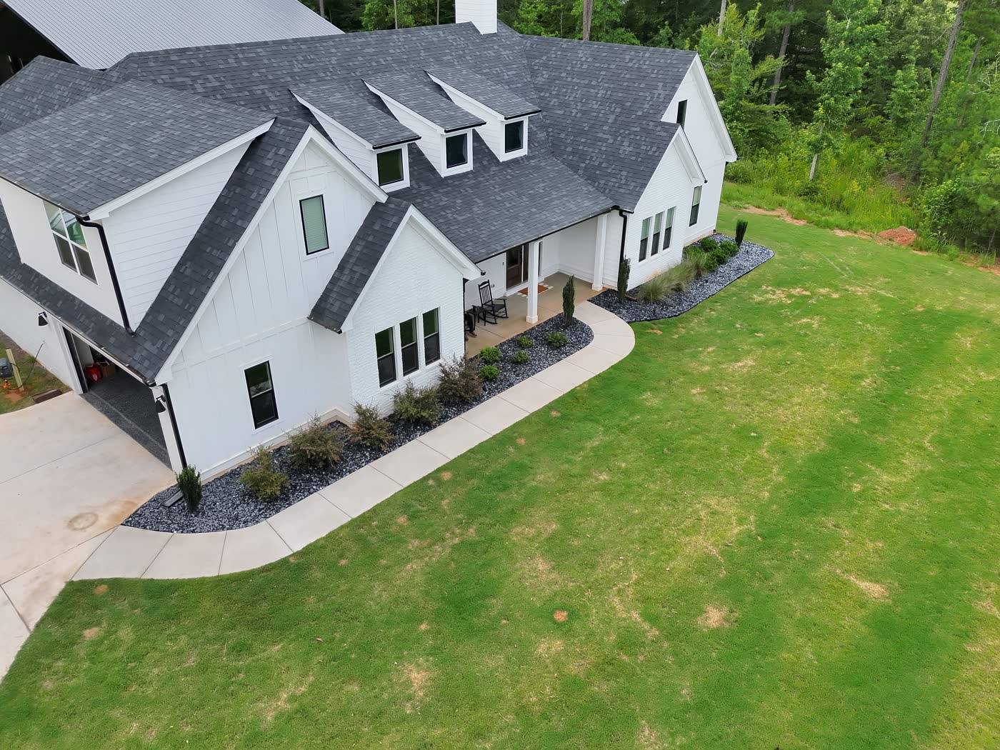 Aerial view of finished lawn and bed work around a white farmhouse