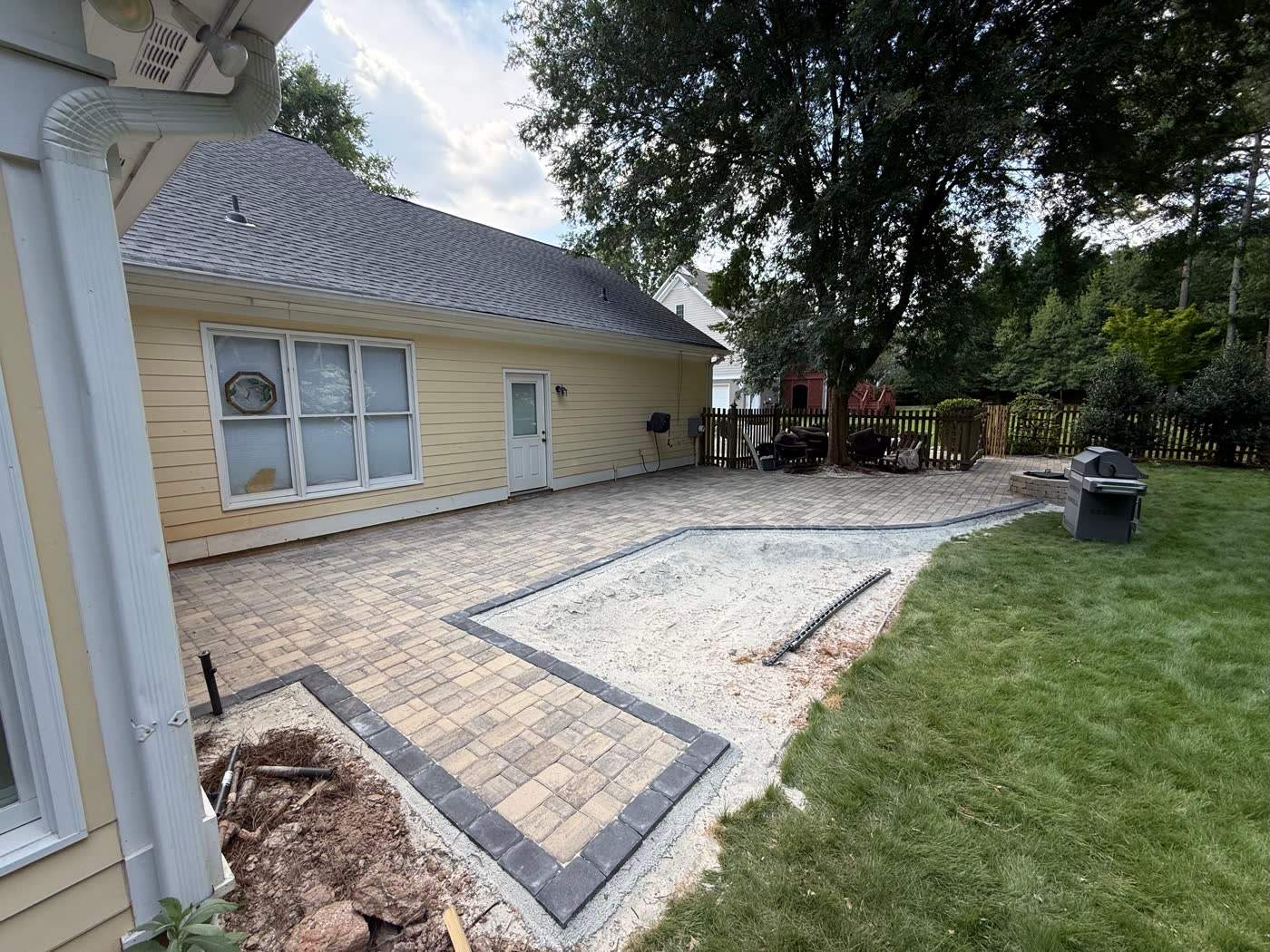 Paver patio meeting fresh lawn at the side of a home