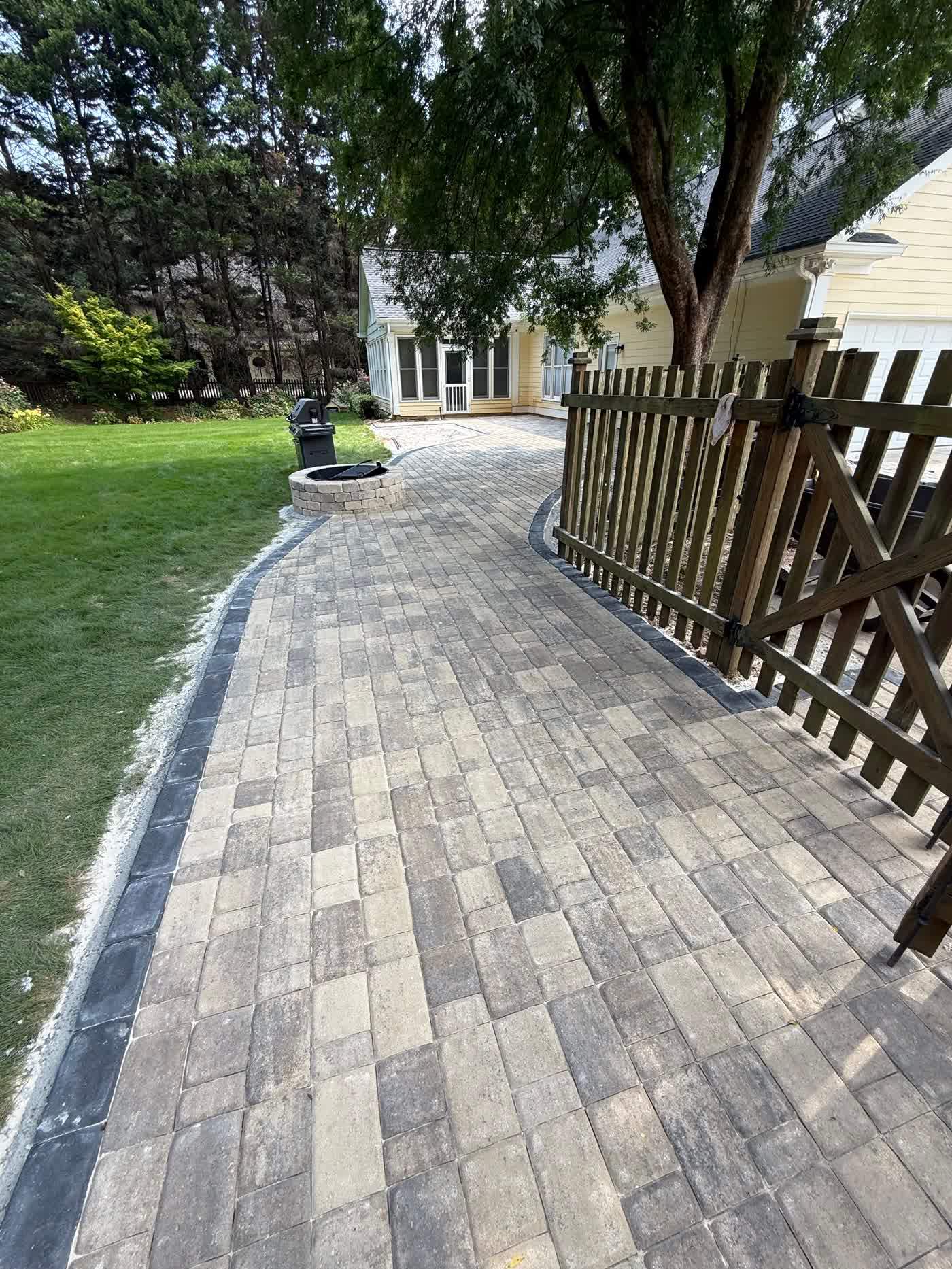 Paver walkway running alongside a wooden fence