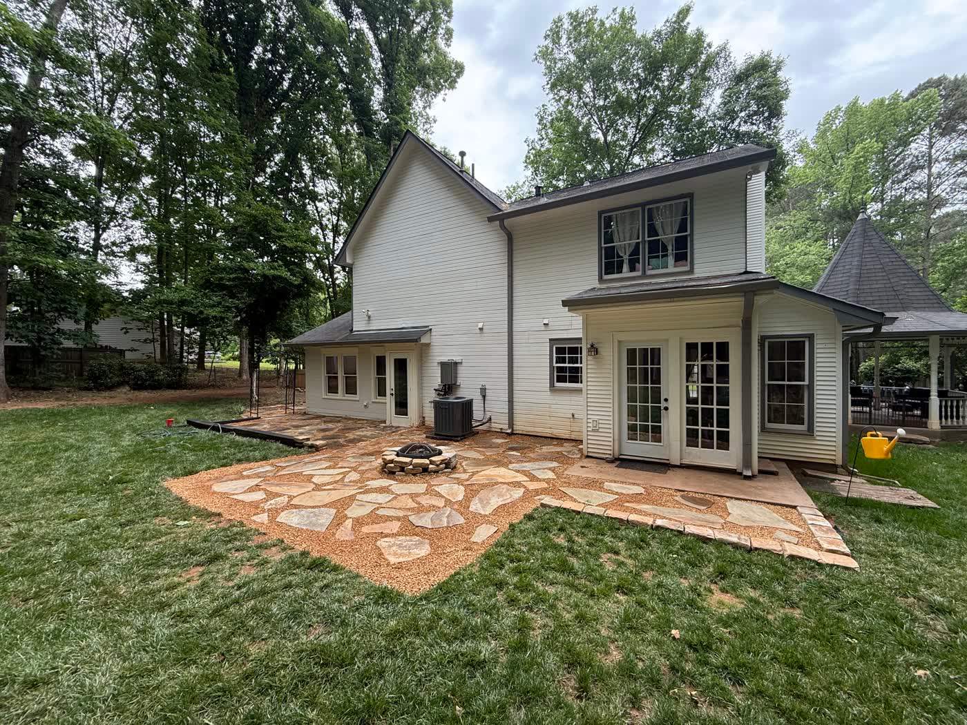 Flagstone patio and fire pit behind a two-story home