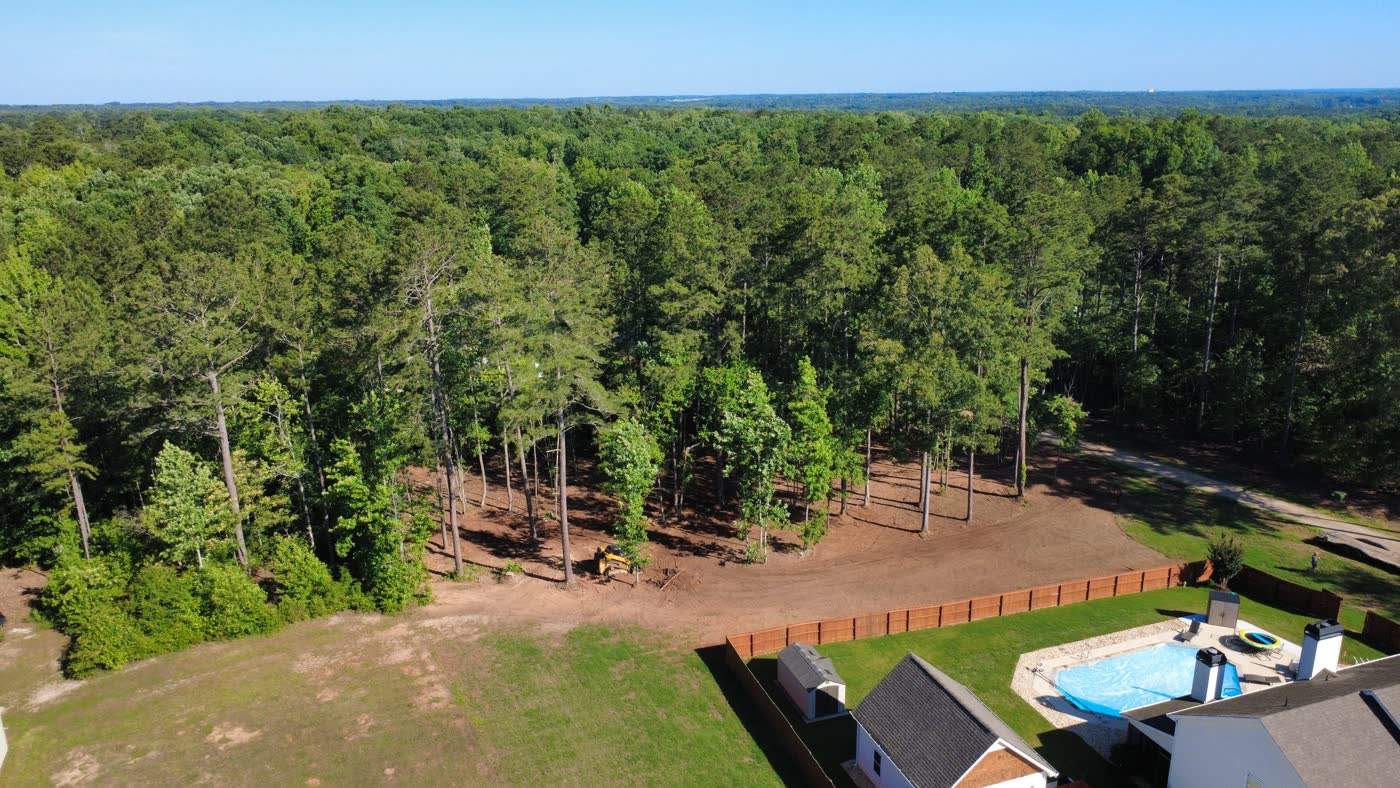 Aerial view of a cleared property line beside a fenced pool yard