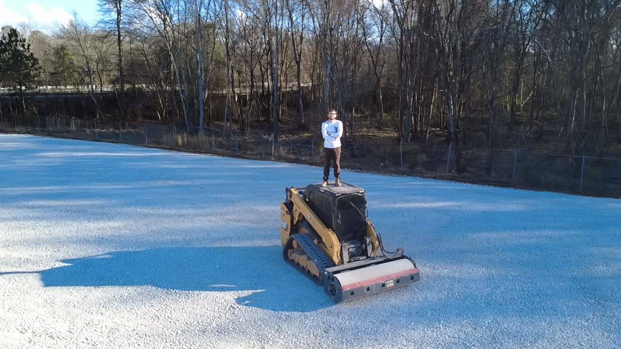 Owner-operator spreading aggregate with a compact roller on a jobsite