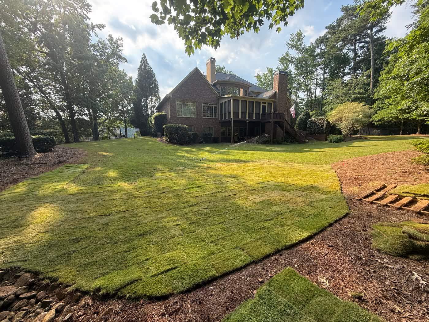 New sod lawn edged with fieldstone beside a home