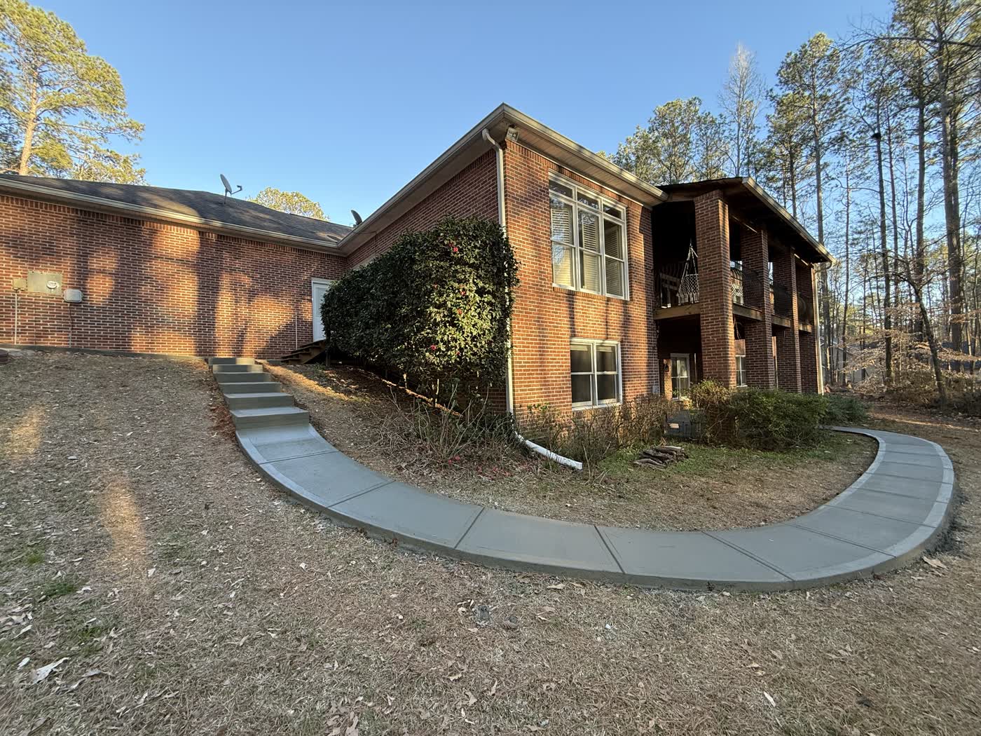 Concrete walkway and steps running along a brick house