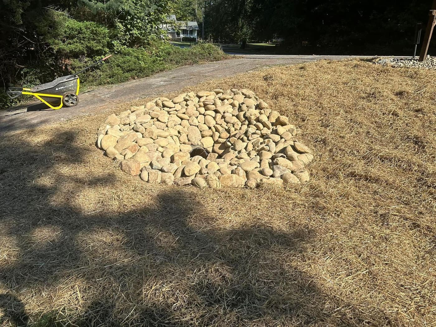 Riprap catch basin in a straw-covered yard