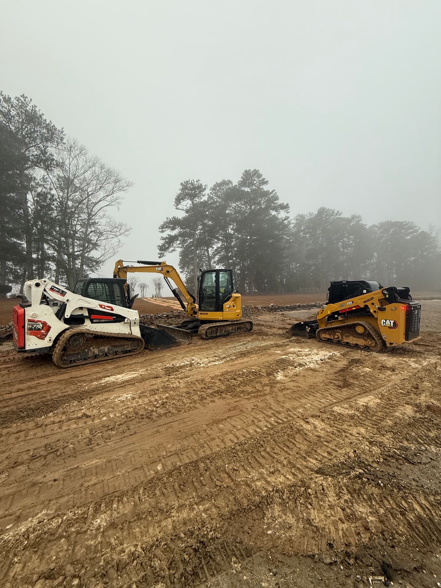 Machines grading a foggy commercial site